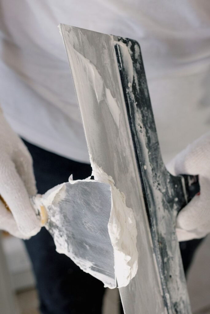 Gloved hands preparing and filling a wall surface